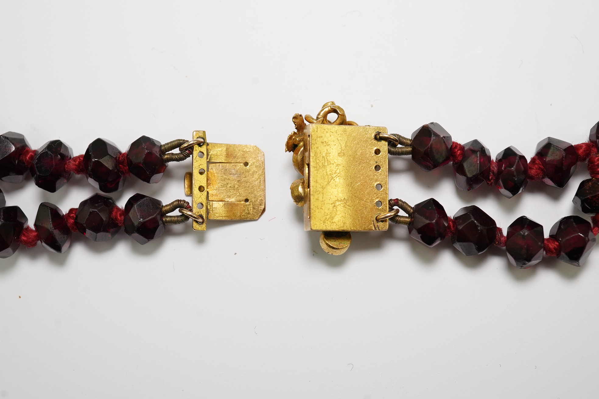 A Victorian facet cut garnet necklace, with cabochon garnet cluster set gold clasp